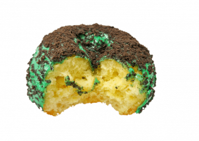 Green mint glazed donut topped with crushed Oreo from Purvé Donut Stop Hawaii with a bite out of it showing the fluffy center