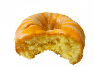 Orange glazed donut topped with a cream cheese drizzle from Purvé Donut Stop Hawaii with a bite out of it showing the fluffy center