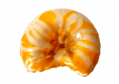 Orange glazed donut topped with a cream cheese drizzle from Purvé Donut Stop Hawaii with a bite out of the side