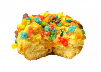 Lemon glazed donut crop dusted with fruity pebbles from Purvé Donut Stop Hawaii with a bite out of it showing the fluffy center